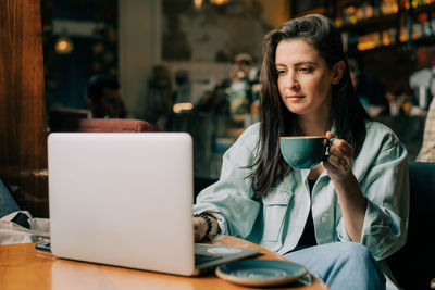 Young woman using mobile phone while sitting on table