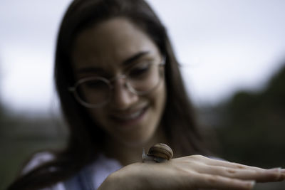 Smiling young woman with snail on hand