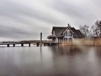 Bridge over river by building against sky