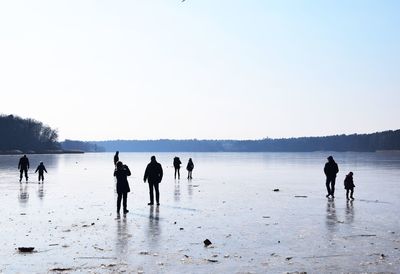 People standing at beach against clear sky