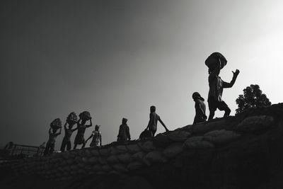 Low angle view of people standing against clear sky