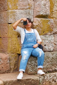 Girl photographing through camera against wall