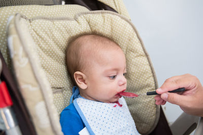 Cropped woman feeding baby boy on baby carriage at home