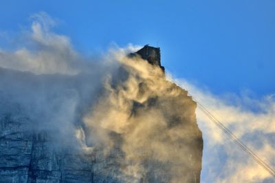 Low angle view of smoke emitting from building against sky