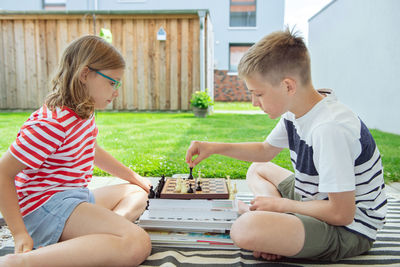 Rear view of father and girl sitting outdoors