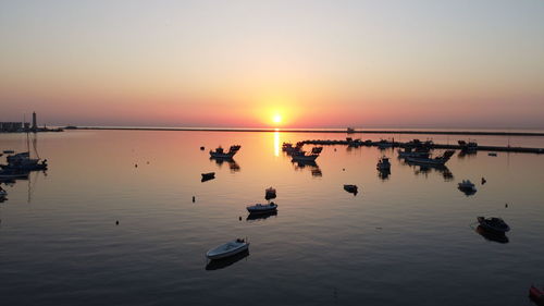Silhouette people on sea against sky during sunset