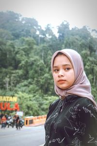 Portrait of young woman standing against mountain