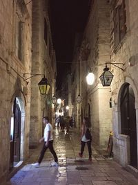 People walking on illuminated street at night