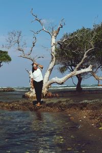 Woman standing by tree against sky