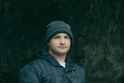 Portrait of man wearing knit hat against rock formation