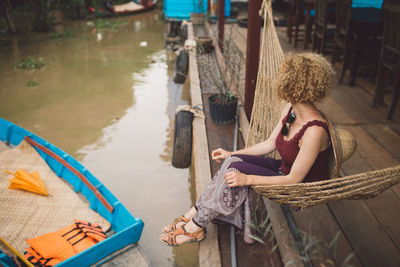 Woman sitting in hammock by canal