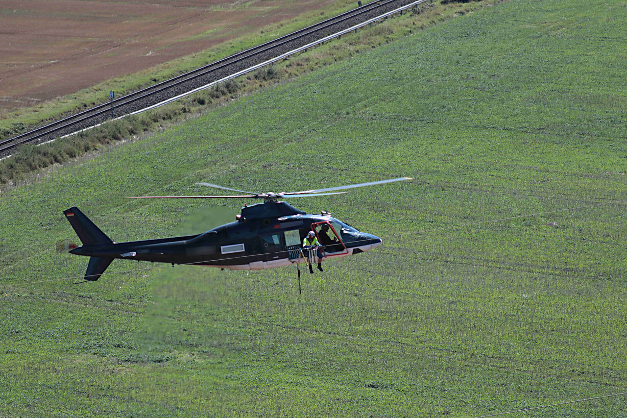 HIGH ANGLE VIEW OF AIRPLANE FLYING OVER LAND ON FIELD