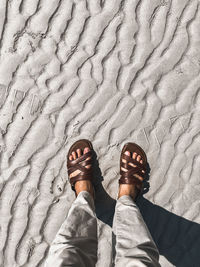 Low section of man standing on sand at beach