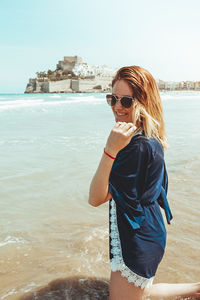 Young woman wearing sunglasses standing on beach