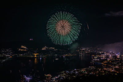 Firework display over city against sky at night