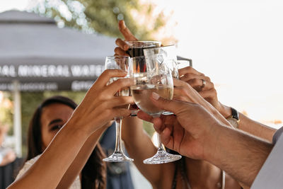 Close-up photo of group of friends clinking glasses, drinking and celebrating