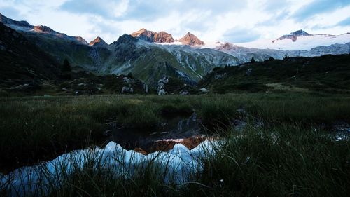 Scenic view of lake by snowcapped mountains against sky