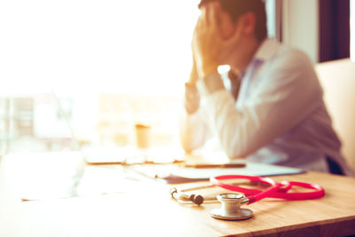 Close-up of stethoscope against tensed male doctor at desk