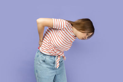 Side view of woman standing against blue background