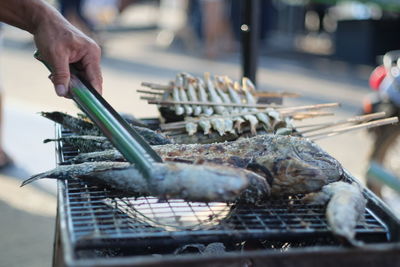 Close-up of man preparing food on barbecue grill