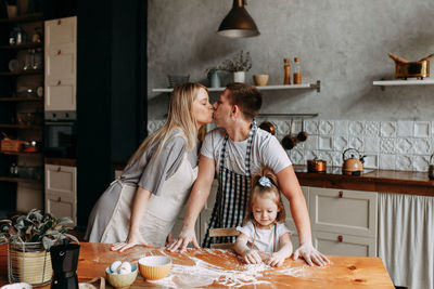 A happy family with a child cook and have fun with flour in a cozy kitchen at home