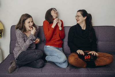 High angle view of friends sitting on sofa at home