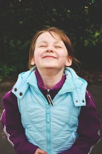 Close-up of child with eyes closed smiling outdoors