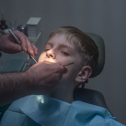 Cropped hands of dentist examining boy at hospital