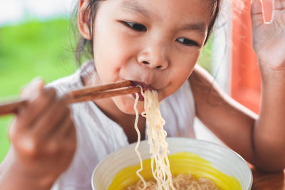 Cute girl eating noodles at table in public park