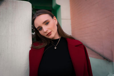 Portrait of a beautiful young woman standing against wall