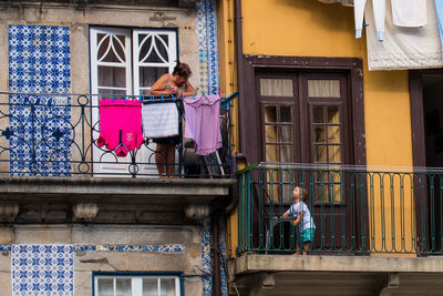 Rear view of two women standing on window of building