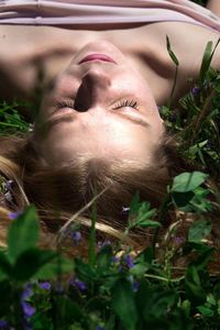 High angle close-up of young woman lying on grassy field