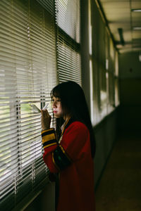 Side view portrait of young woman standing against wall