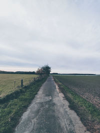 Road amidst field against sky