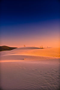 Scenic view of land against clear sky during sunset