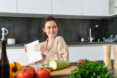 Portrait of smiling young woman using digital tablet while sitting on table