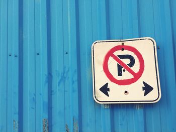 Low angle view of no parking sign on blue corrugated iron