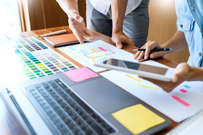 Midsection of design professionals working on desk in office