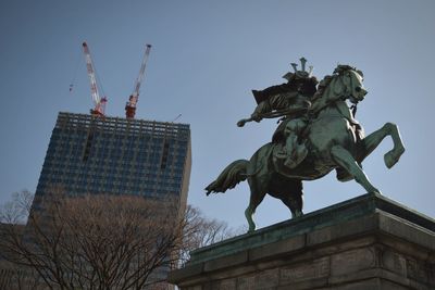 Low angle view of statue against building in city against sky