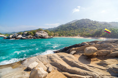 Colombian flag on rock in sea at tayrona national park