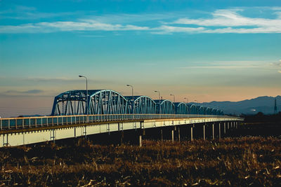 Train on bridge against sky during sunset