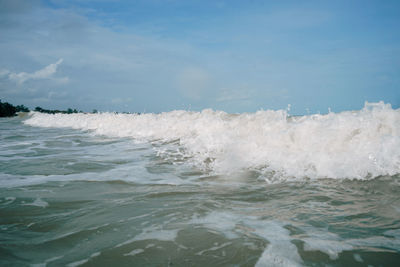 Waves splashing on sea against sky