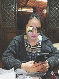 Portrait of woman in sunglasses using smart phone at restaurant