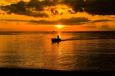 Silhouette boat in sea against orange sky