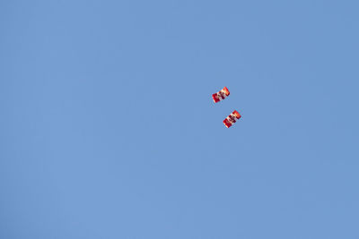 Low angle view of red balloons flying against clear blue sky