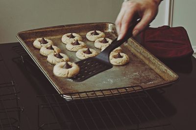 Cropped hand picking cookie from baking sheet with spatula