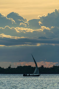 Silhouette sailboat in sea against sky during sunset