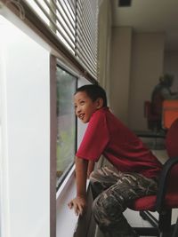 Portrait of boy sitting by window at home