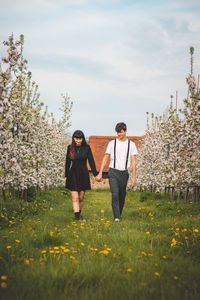 Young strong love between two young people walking under apple trees. candid portrait of a couple