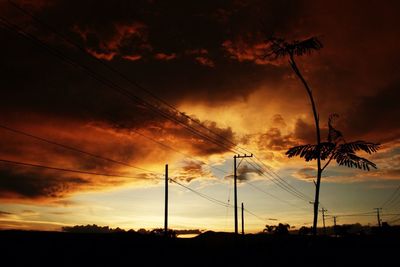 Low angle view of electricity pylon against cloudy sky